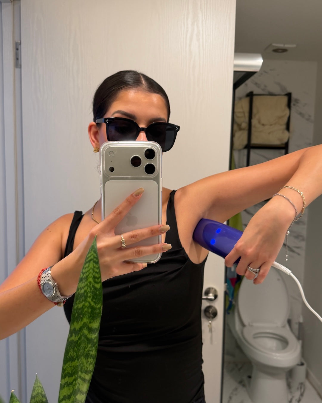Mujer en baño tomando selfie en el espejo aplicando la SkinUp Pro en la axila